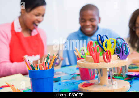 Insegnanti e studenti in classe d'arte con forniture in primo piano (messa a fuoco selettiva) Foto Stock