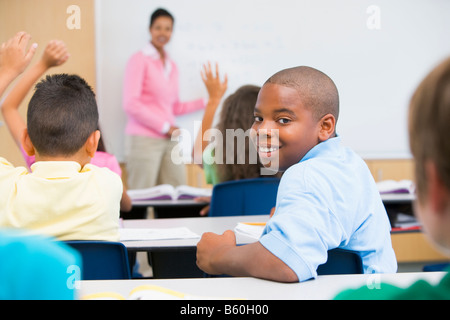 Studente in classe guardando la fotocamera con insegnante di sfondo (il fuoco selettivo) Foto Stock