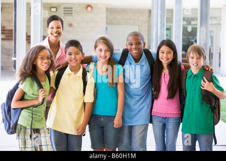 Sei studenti in piedi al di fuori della scuola con l'insegnante Foto Stock