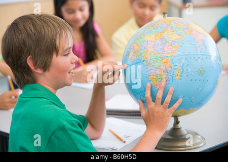 Studente in classe il puntamento su un globo (messa a fuoco selettiva) Foto Stock