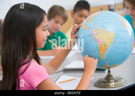 Studente in classe il puntamento su un globo (messa a fuoco selettiva) Foto Stock