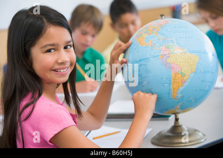 Studente in classe il puntamento su un globo (messa a fuoco selettiva) Foto Stock