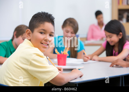 Gli studenti in classe a prendere appunti con insegnante di sfondo (il fuoco selettivo) Foto Stock