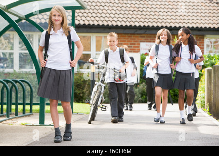 Gli studenti che lasciano la scuola con una bicicletta Foto Stock