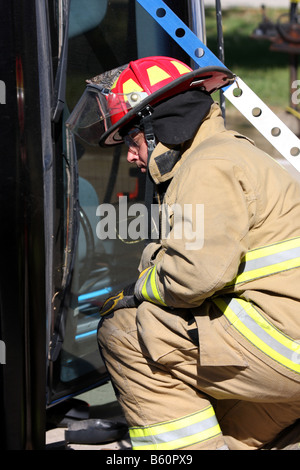 Un vigile del fuoco guardando la parte anteriore del cofano di una vettura che si è ribaltata e deve essere stabilizzata prima extrication Foto Stock