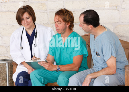 Tre infermieri seduta su una panchina discutendo della carta di lavoro Foto Stock