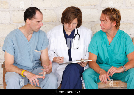 Tre infermieri seduta su una panchina discutendo della carta di lavoro Foto Stock