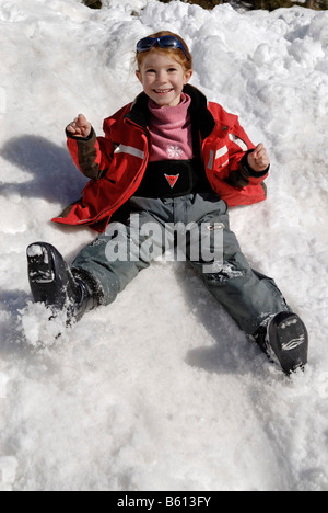 Ragazza ridere lo scorrimento verso il basso una coperta di neve hill, giocare nella neve Foto Stock