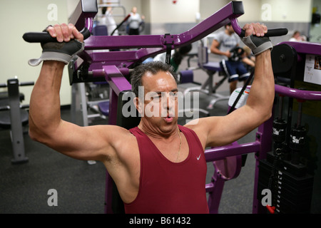 Un 61-anno-vecchio uomo lavora in una palestra. L'uomo, che ha una storia familiare di malattia cardiaca funziona a migliorare le sue condizioni di salute. Foto Stock