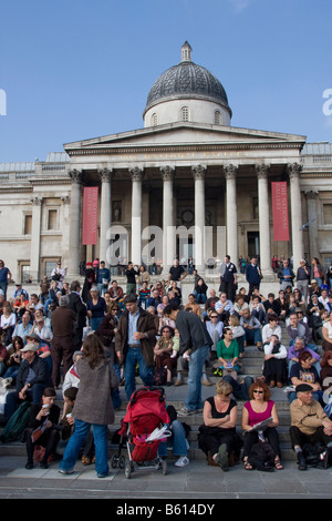 Turisti che si siedono sui gradini al di fuori della Galleria Nazionale in Trafalgar Square Londra GB UK Foto Stock