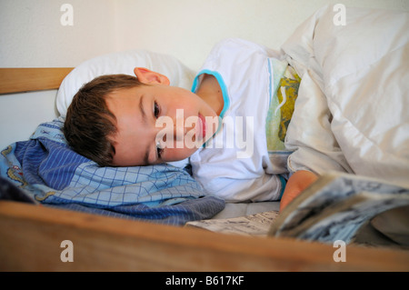 Ragazzo giacente in un letto e la lettura Foto Stock