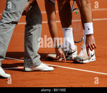 Arbitro contestato la decisione ad una partita di tennis, arbitro che mostra un giocatore di tennis con l'indice della mano sinistra la linea del campo da tennis Foto Stock