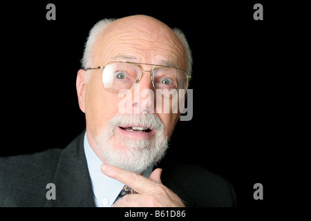 Un bel illustri cercando senior uomo su uno sfondo nero cercando sorpreso Foto Stock