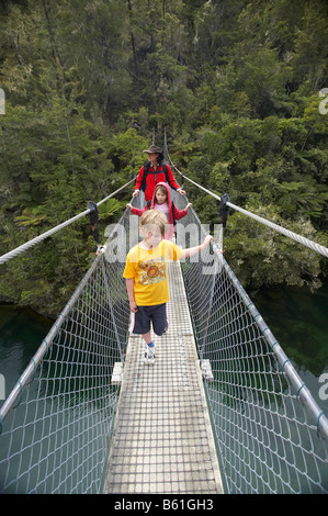 Famiglia a piedi la Abel Tasman via costiera a Falls River sospensione ponte Nelson regione Isola del Sud della Nuova Zelanda Foto Stock