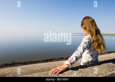 Ragazza guardando dal terrapieno sopra il mare del Nord, Roemoe, Danimarca, Europa Foto Stock