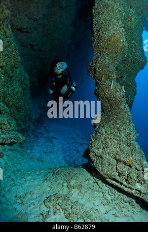 Sub femmina con una lampada guardando stalctites stalgmites e che sono uniti insieme in corrispondenza di una profondità di 45m nel buco blu nati Foto Stock