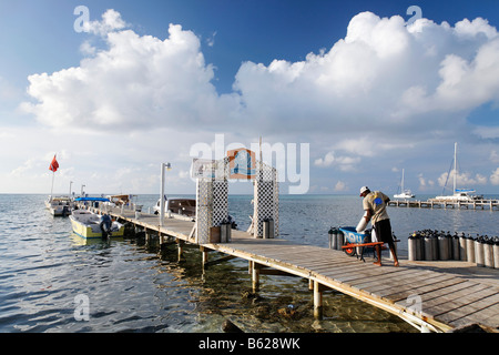 Attrezzatura subacquea viene caricata in un carrello da un uomo su un molo, San Pedro, Ambergris Cay Isola, Belize, America Centrale Foto Stock