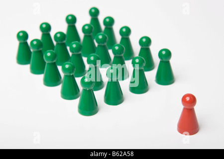 Verde di pezzi di gioco in piedi ordinati insieme con un unico red gaming pezzo davanti, simbolico di erogare un discorso o in pullman Foto Stock
