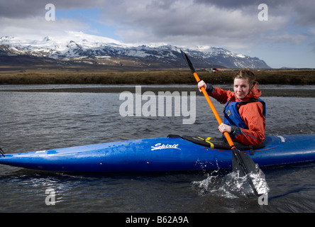 Ragazza adolescente kayak in fiume con Oraefajokull ghiacciaio in background, Islanda Orientale Foto Stock