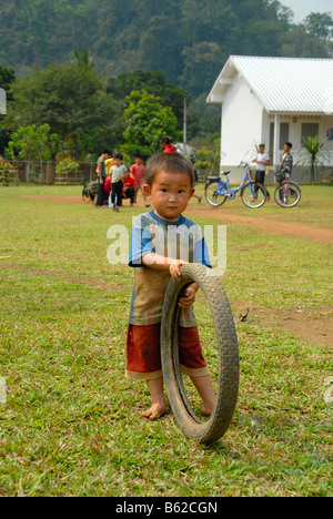 Bambino che gioca con un vecchio pneumatico di fronte a una scuola, Khmu persone borgo vicino a Luang Prabang, Laos, sud-est asiatico Foto Stock