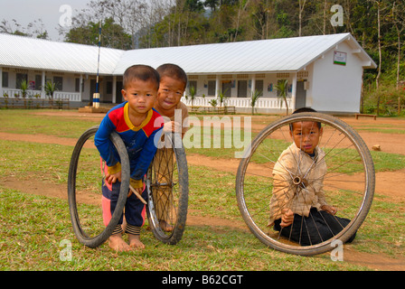 I bambini a giocare con vecchi pneumatici nella parte anteriore di una scuola, Khmu persone borgo vicino a Luang Prabang, Laos, sud-est asiatico Foto Stock