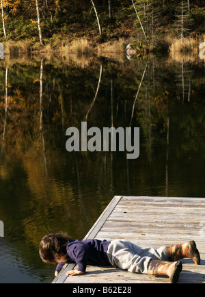 3 anno vecchio ragazzo mix eurasiatica ma guarda caucasian su un molo su un lago di montagna in background con i colori dell'autunno Foto Stock