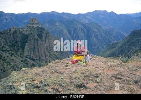 Un Tarahumara donna indiana e suo figlio intreccio cesti per i visitatori sul cerchio Canyon di rame Barrancas del Cobre, Messico. Foto Stock