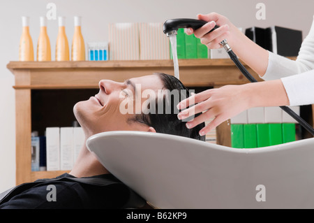 Metà uomo adulto avente capelli lavati in parrucchiere Foto Stock