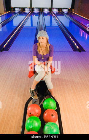 Ragazza seduta in una pista da bowling e di pensiero Foto Stock