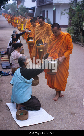 Lo zafferano-derubato i monaci buddisti ricevere elemosina all'alba a Luang Prabang, ex capitale reale del Laos Foto Stock