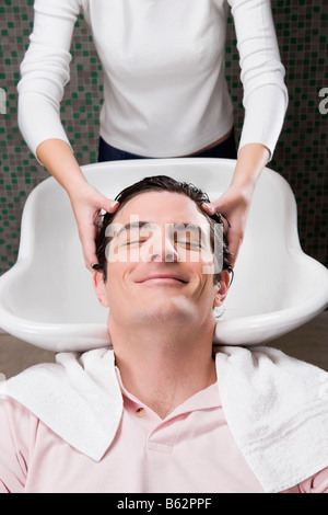 Metà uomo adulto avente un lavare i capelli nel salone di parrucchiere Foto Stock