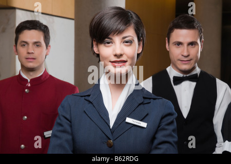 Ritratto di un receptionist in piedi con due camerieri Foto Stock