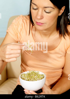 Giovane donna di mangiare germogli alfalfa modello rilasciato Foto Stock