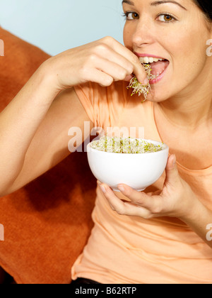 Giovane donna di mangiare germogli alfalfa modello rilasciato Foto Stock