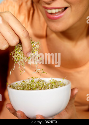 Giovane donna di mangiare germogli alfalfa modello rilasciato Foto Stock