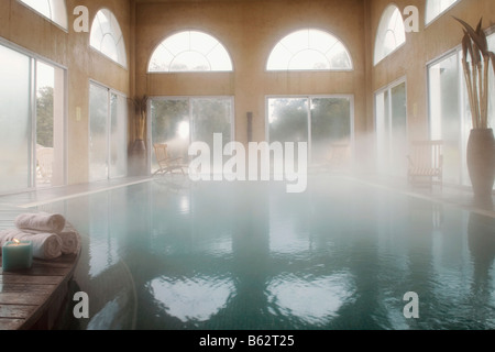 Pila di arrotolato asciugamani e una candela che brucia a bordo piscina Foto Stock