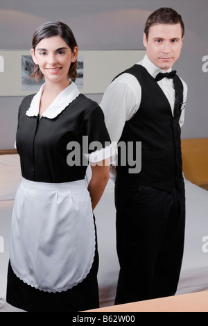 Ritratto di un cameriere e una cameriera in piedi in una stanza di un hotel Foto Stock