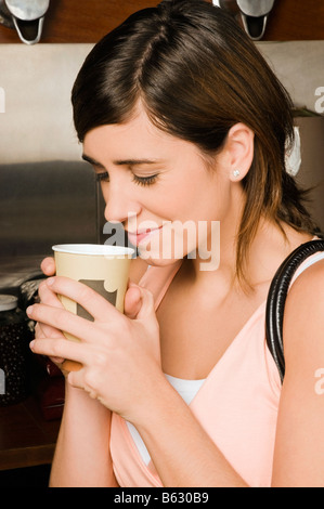 Giovane donna in possesso di una tazza monouso Foto Stock