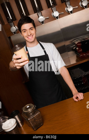 Cafe proprietario in possesso di una tazza monouso a un contatore Foto Stock