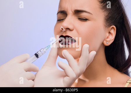 Close-up di un chirurgo la mano di iniettare su una giovane donna di labbra Foto Stock