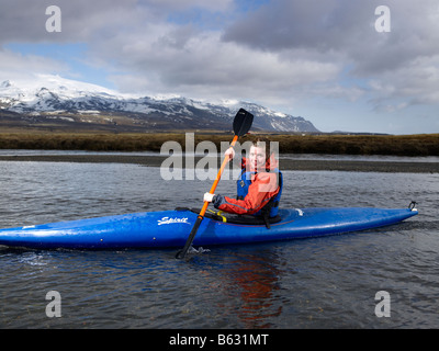 Ragazza adolescente kayak in fiume con Oraefajokull ghiacciaio in background, Islanda Orientale Foto Stock