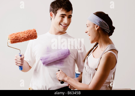 Coppia giovane azienda rulli di vernice e sorridente Foto Stock