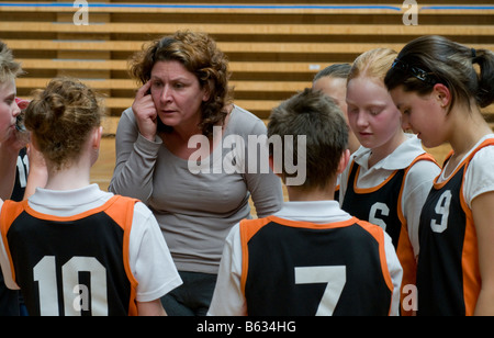 Pullman a discutere di tattiche con i giocatori di un misto di junior scuola primaria squadra di basket Foto Stock