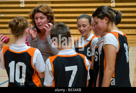 Pullman a discutere di tattiche con i giocatori di un misto di junior scuola primaria squadra di basket Foto Stock