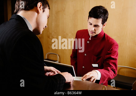 Imprenditore il controllo di una card presso la reception dell'hotel Foto Stock