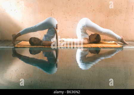 Profilo laterale di due giovani donne che esercitano presso la piscina Foto Stock