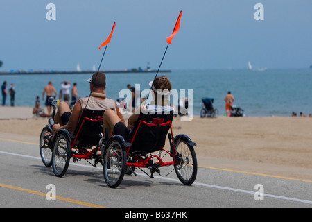 Vista posteriore di due uomini su un triciclo, Oak Street Beach, Lake Shore Drive, Chicago, Illinois, Stati Uniti d'America Foto Stock