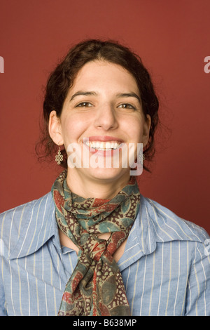 Ritratto di una giovane donna su uno sfondo di colore rosso che indossa una sciarpa Foto Stock