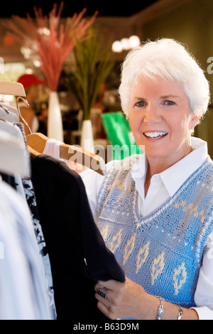Ritratto di una donna senior scegliendo i vestiti in un negozio di abbigliamento Foto Stock