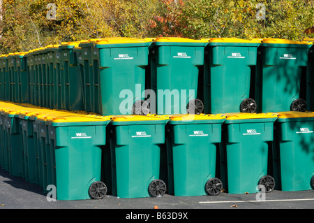 Grande gruppo di molti nuovi di plastica nel cestino di riciclaggio di barili o scomparti wheelie verde giallo con coperchi impilati in parcheggio Foto Stock